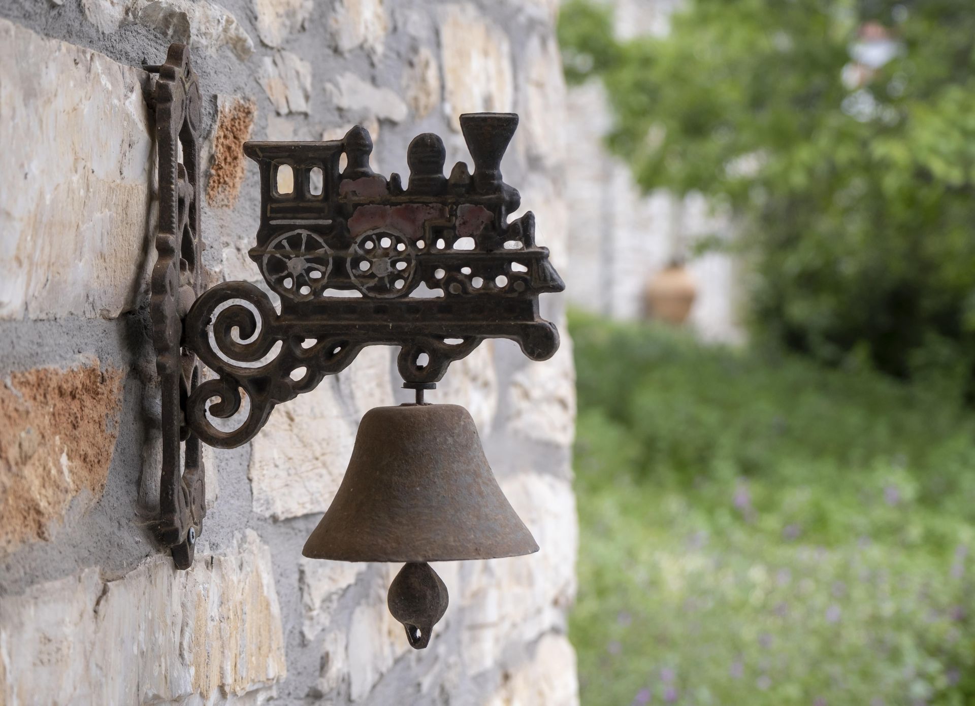 Cast iron train-shaped doorbell on a stone wall.