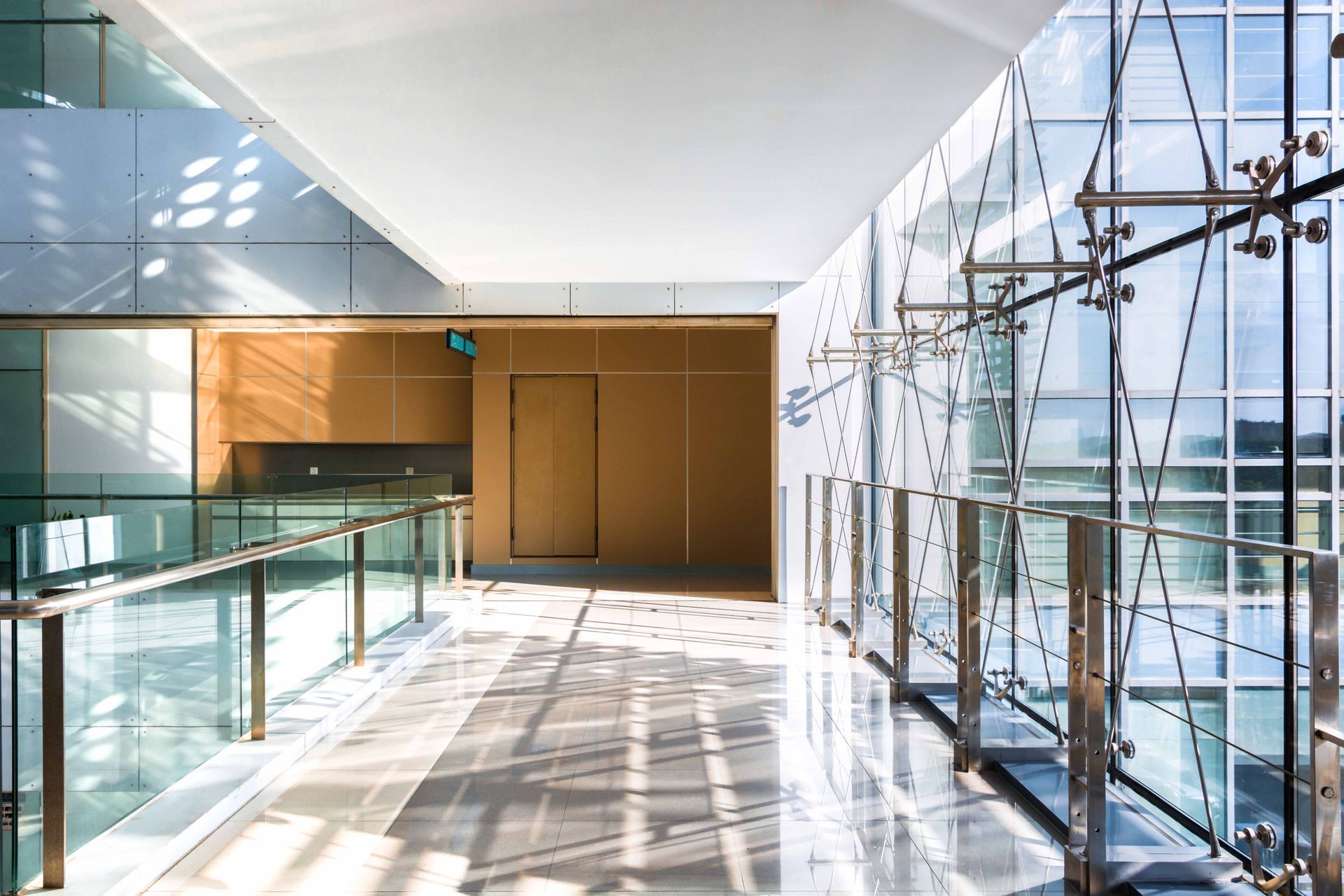 Modern hallway with glass walls, metal railings, and natural light.