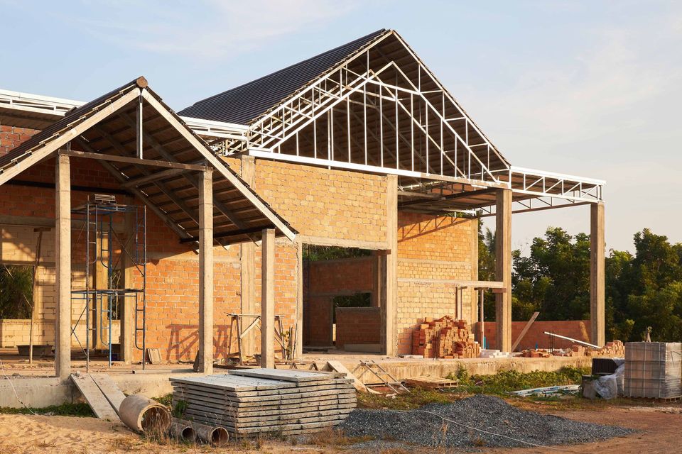 Building under construction, brick walls, steel frame roof, piles of bricks and building materials.