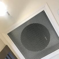 Ceiling vent with grid pattern and circular opening, likely for air circulation.
