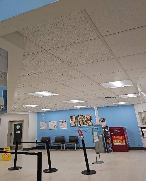 Waiting area with blue wall, posters, chairs, and ceiling tiles.