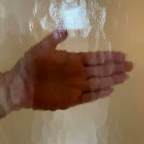 Hand pressed against a blurry, textured surface.