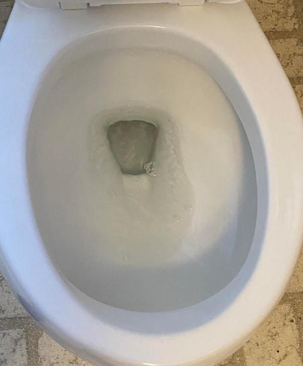 A white toilet bowl filled with swirling, clear water.