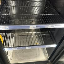 Empty, open commercial freezer with wire shelves.
