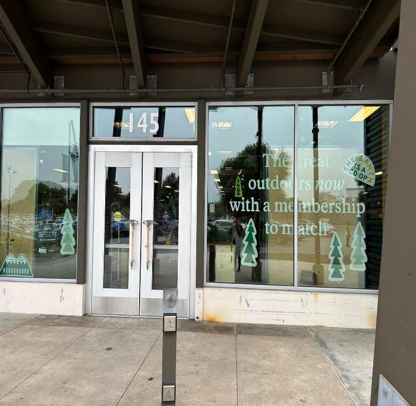 Exterior of store with glass doors, number 145, and windows with advertisement about outdoor memberships.