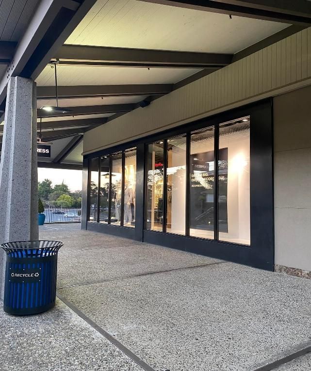 Exterior of a storefront with large windows and a covered walkway.