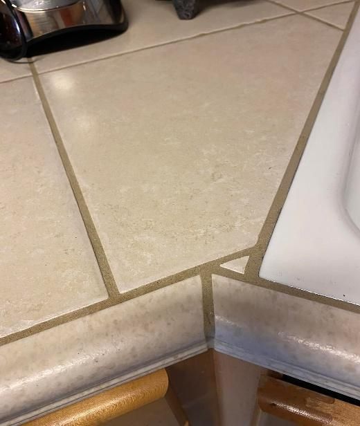 Beige tiled kitchen countertop with brown grout lines.
