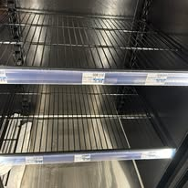 Empty metal shelves in a commercial refrigerator.