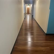 Long hallway with polished, dark wood floor.