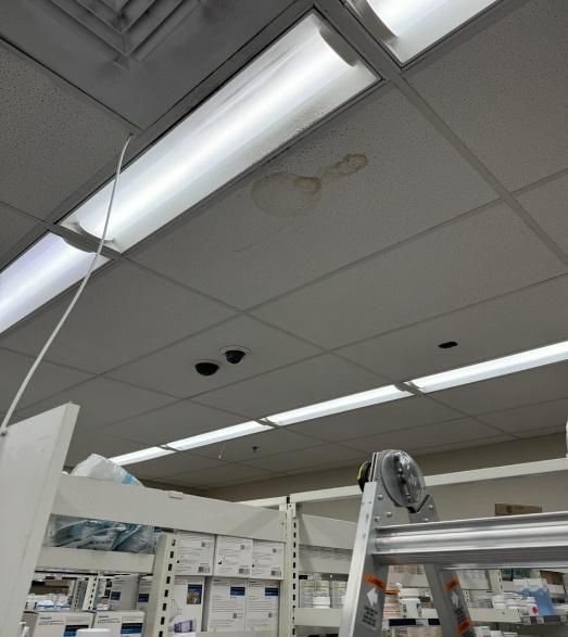 Ceiling tiles with a water stain and fluorescent lights in a retail store setting.