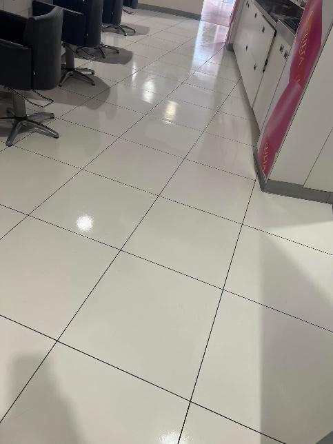 White tiled floor in a salon with chairs and a cabinet.