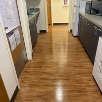 A hallway with brown flooring, gray cabinets, and a bulletin board on the left wall.