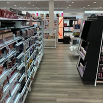 Cosmetics store interior with shelves of makeup products and display stands.