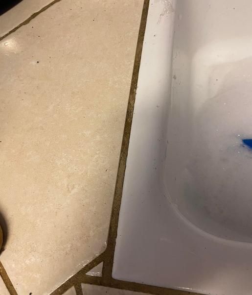Tan tile floor and white sink, with dark grout visible between the tiles.