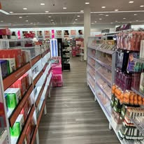 Shelves of cosmetics in a well-lit store, with a wooden floor.