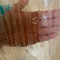 Hand covered in soap bubbles pressed against a textured shower curtain.