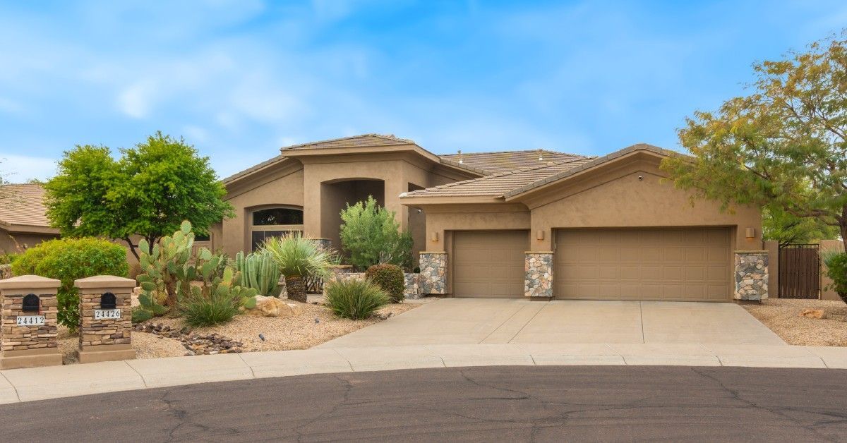 A modern, luxury residential property with xeriscaping landscaping and a bright blue sky above .