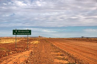 A Dirt Road with A Green Sign in The Middle of It — North West Queensland Painting in Birdsville, QLD