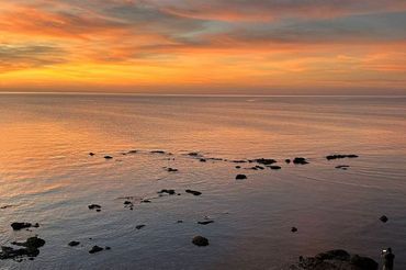 A Sunset Over a Large Body of Water with Rocks in The Foreground — North West Queensland Painting in Mornington Island, QLD