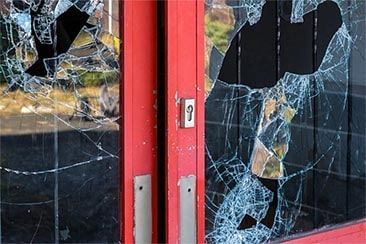 A red door with broken glass on it