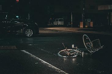A bicycle is laying on the ground on the side of the road.