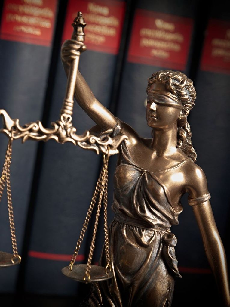 A statue of lady justice standing in front of books