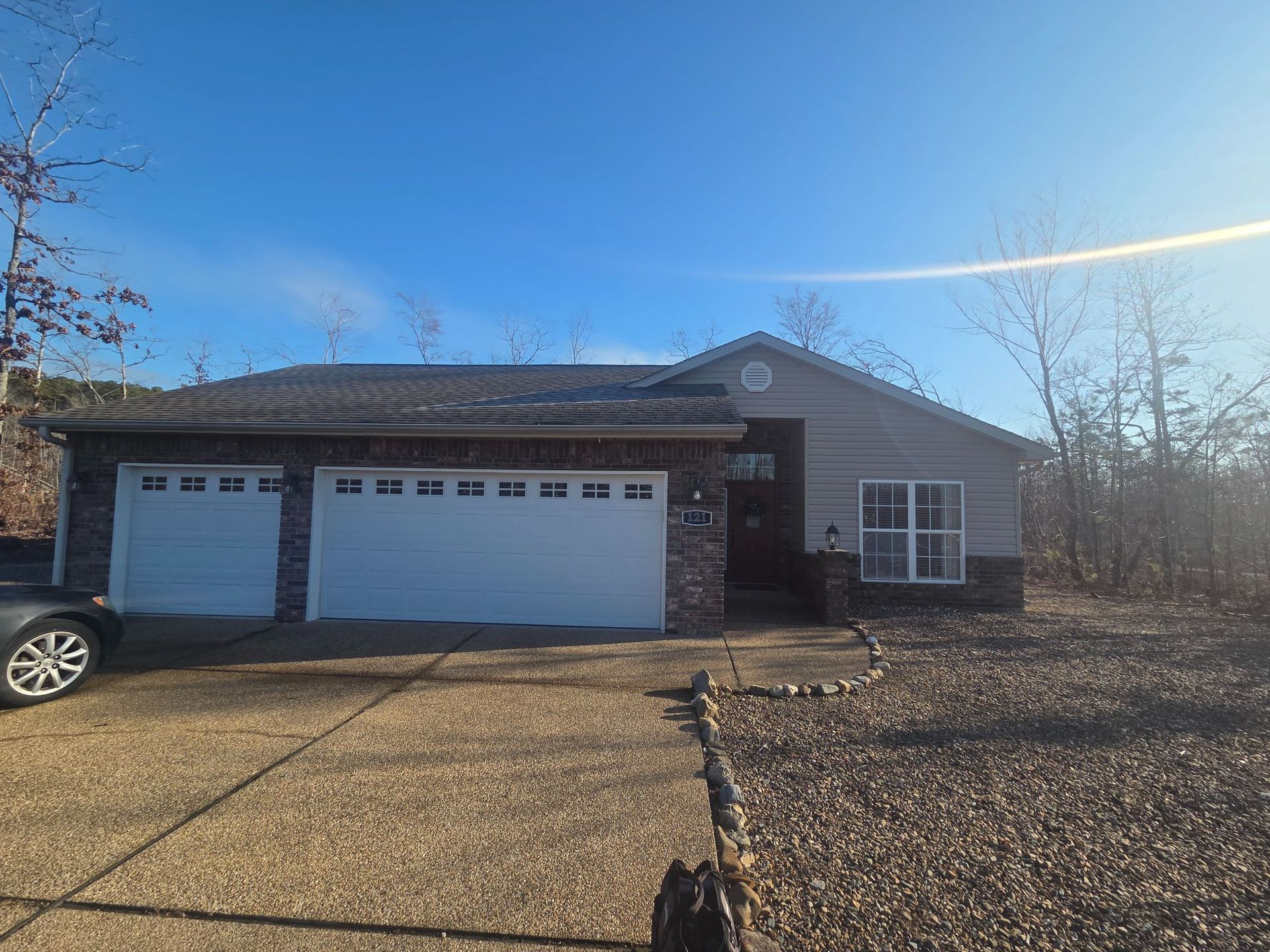 Ranch-style house with stone accents, a two-car garage, and a driveway on a sunny day.