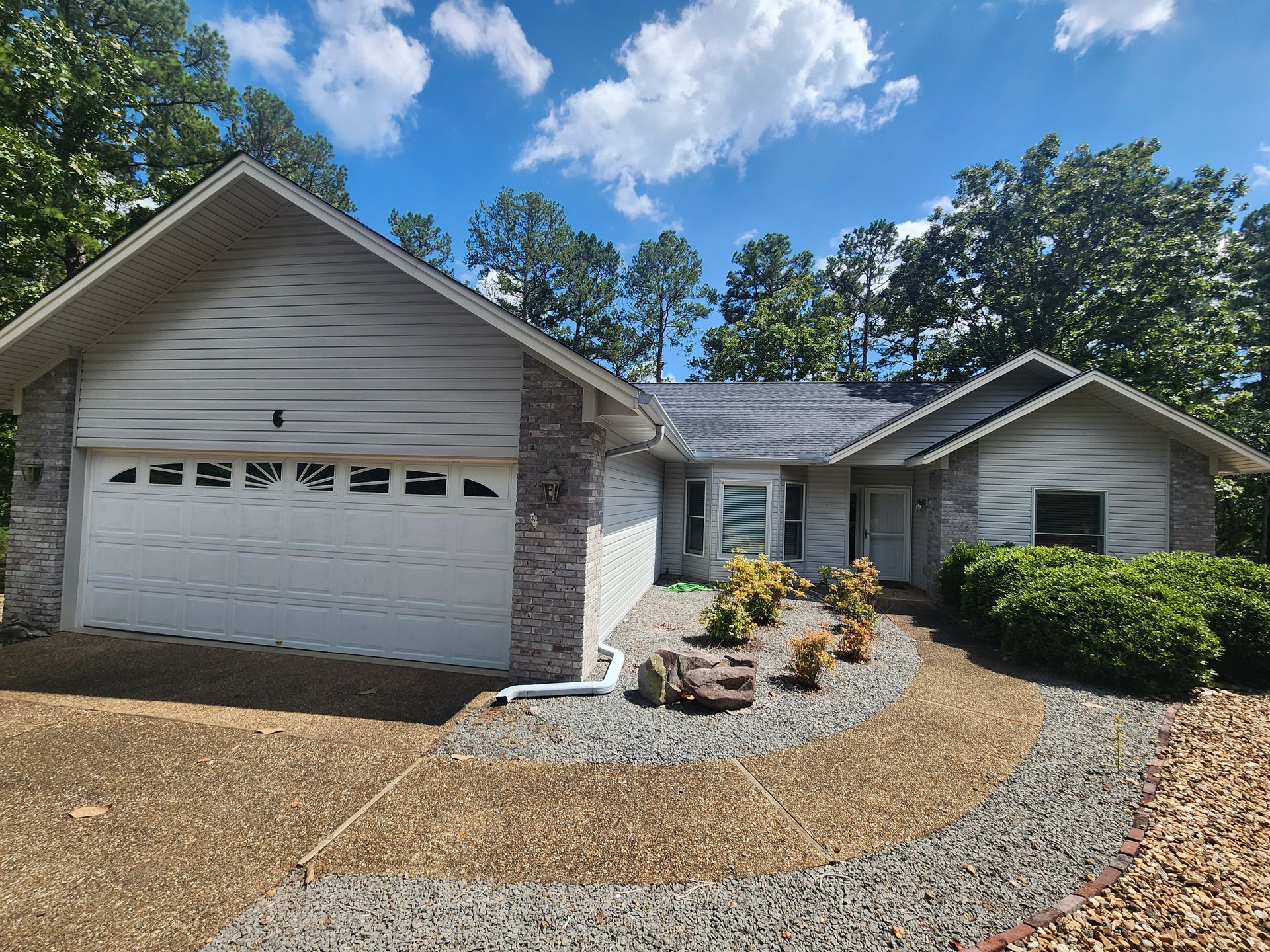 A white house with a gray roof and a white garage door
