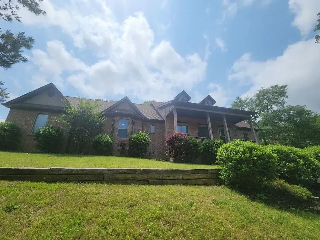 A large brick house is sitting on top of a lush green hill.