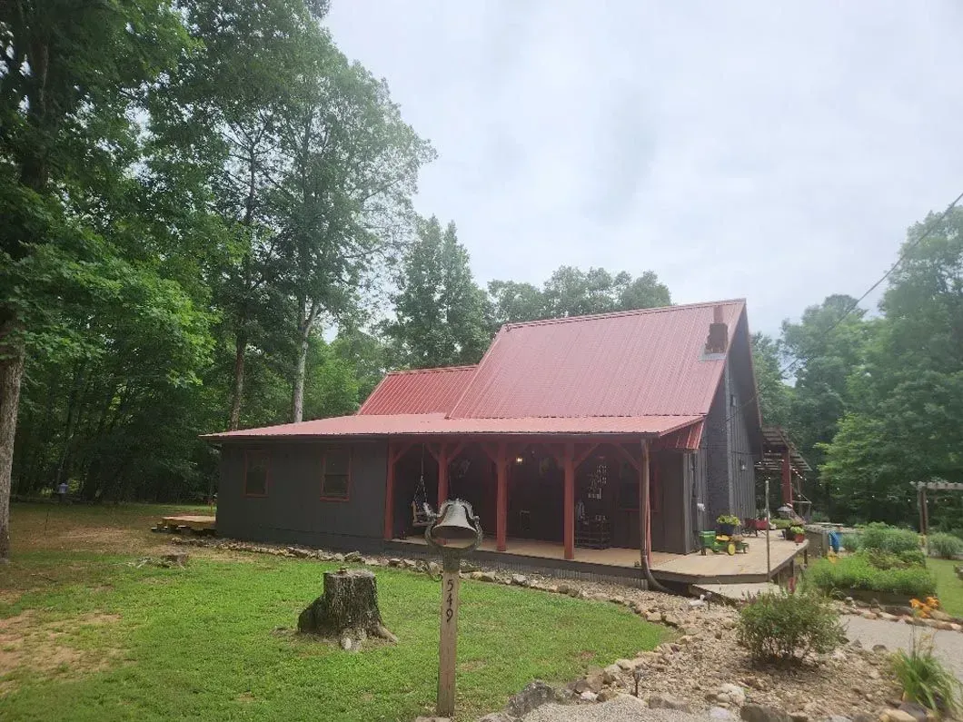 A small house with a red roof is surrounded by trees.