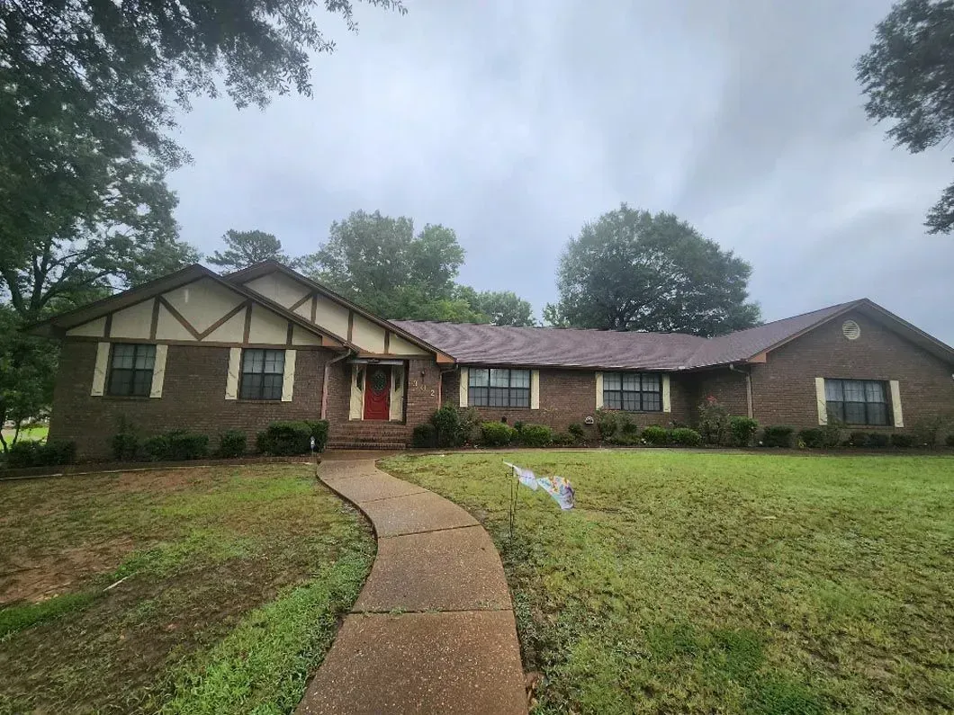 A large brick house with a red door and a walkway leading to it.