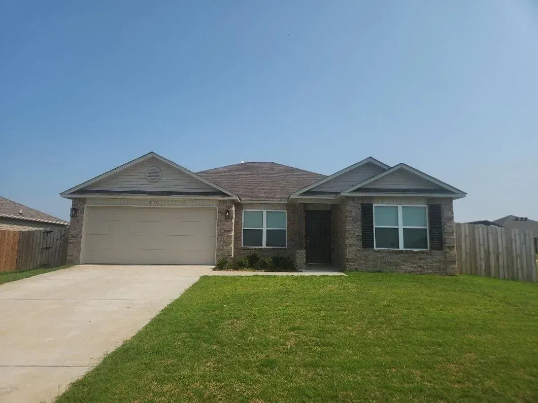 A house with a large driveway and a large lawn in front of it.