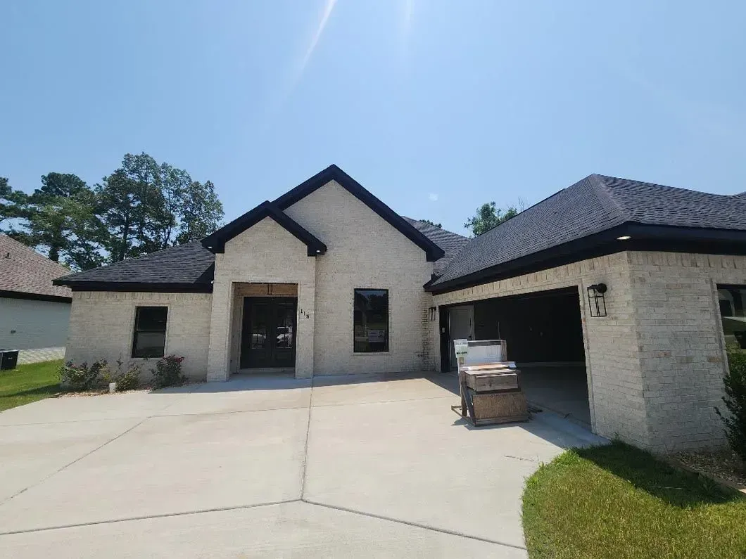 A large white brick house with a black roof and a garage.