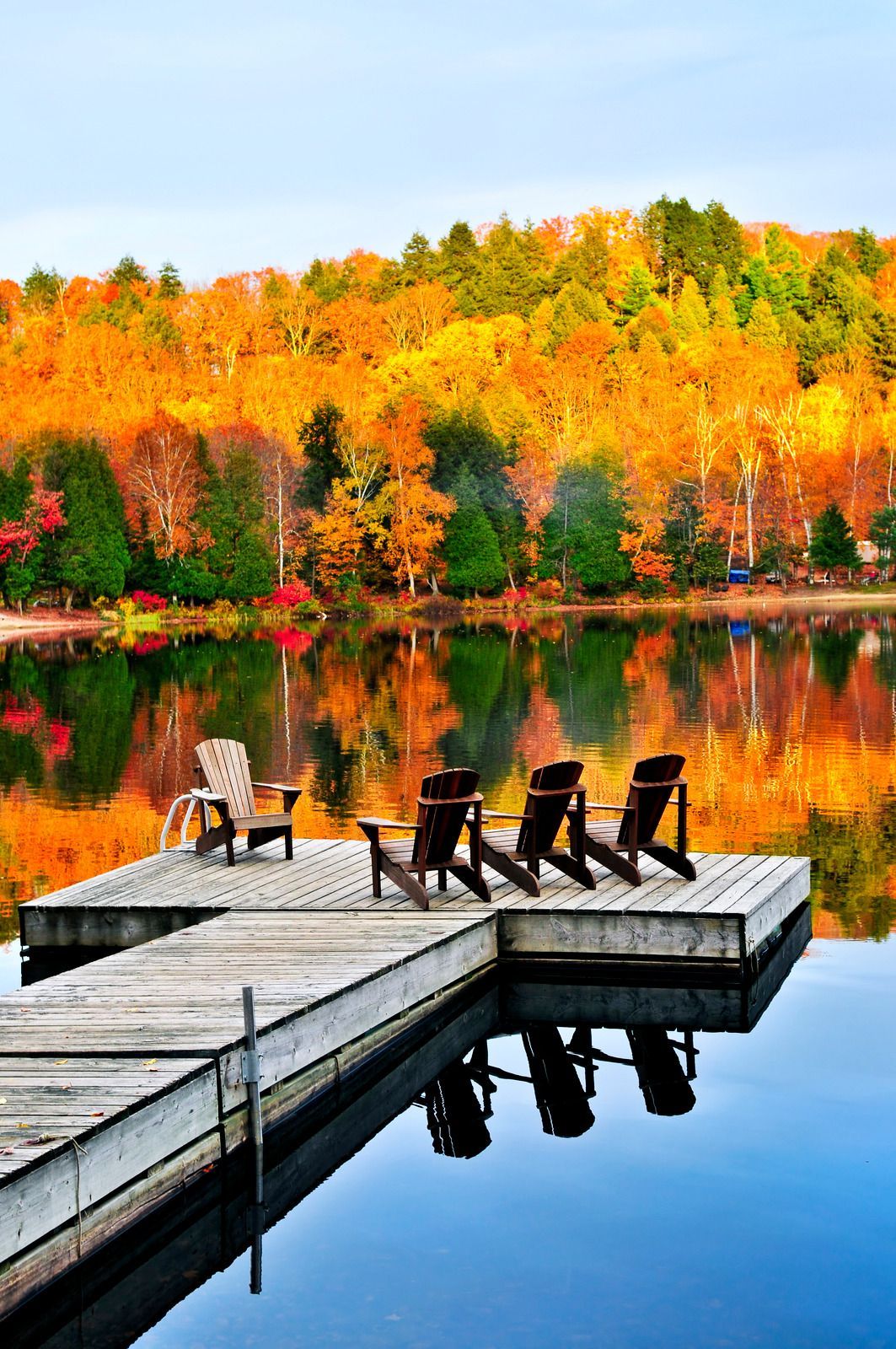 Two chairs are sitting on a dock overlooking a lake.
