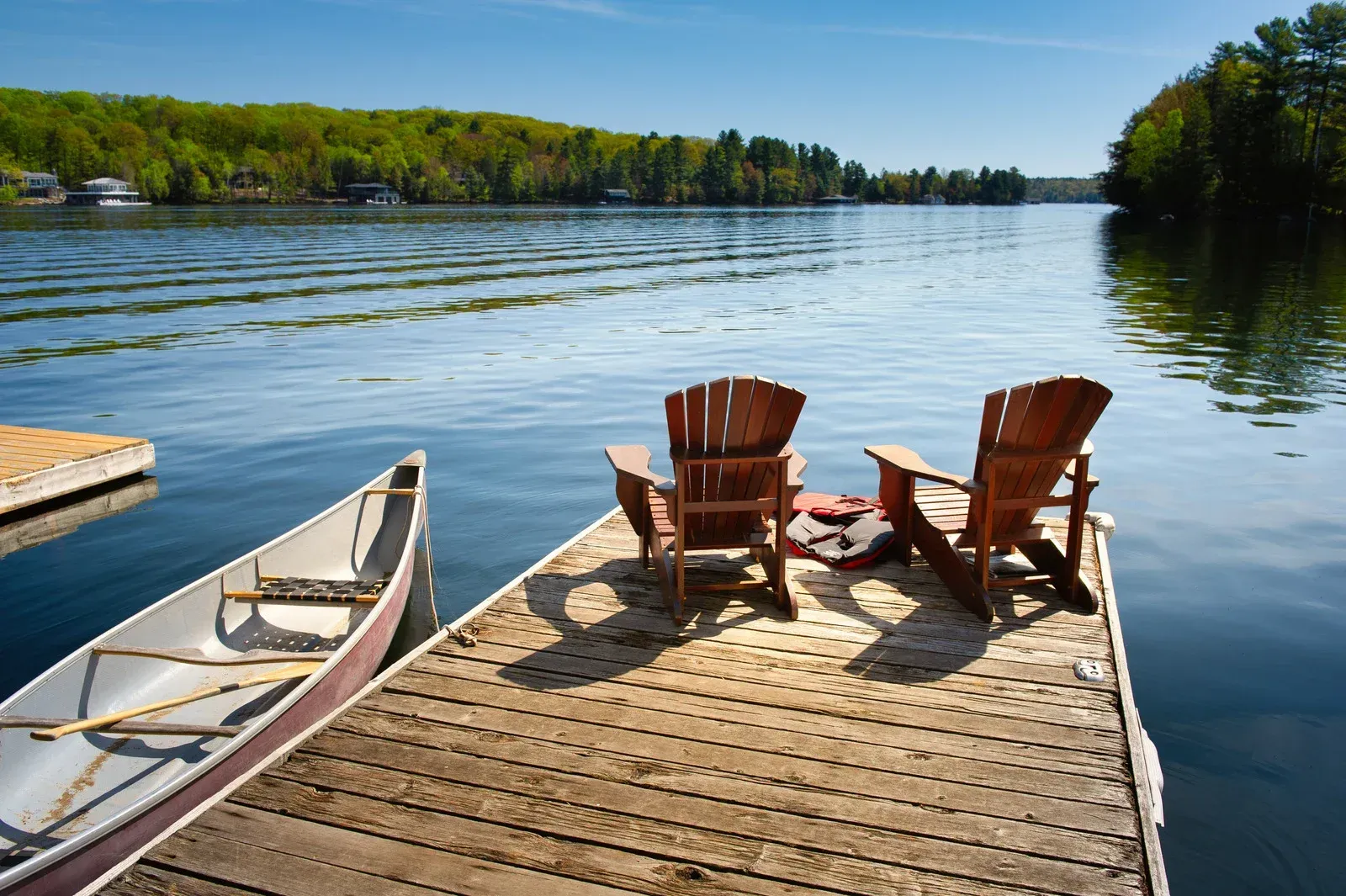 Two chairs are sitting on a dock next to a canoe.