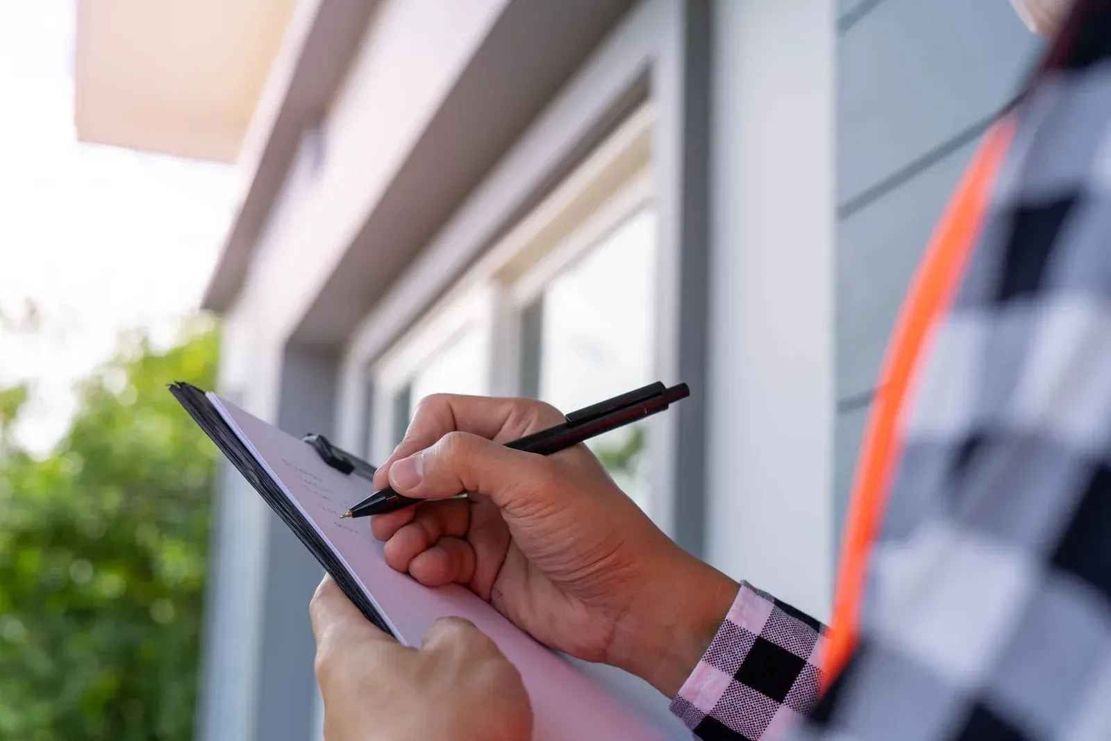 A man is writing on a clipboard with a pen.