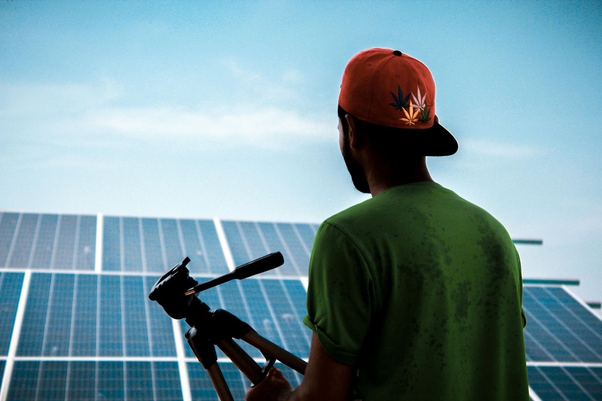 A man is standing in front of a solar panel holding a camera.