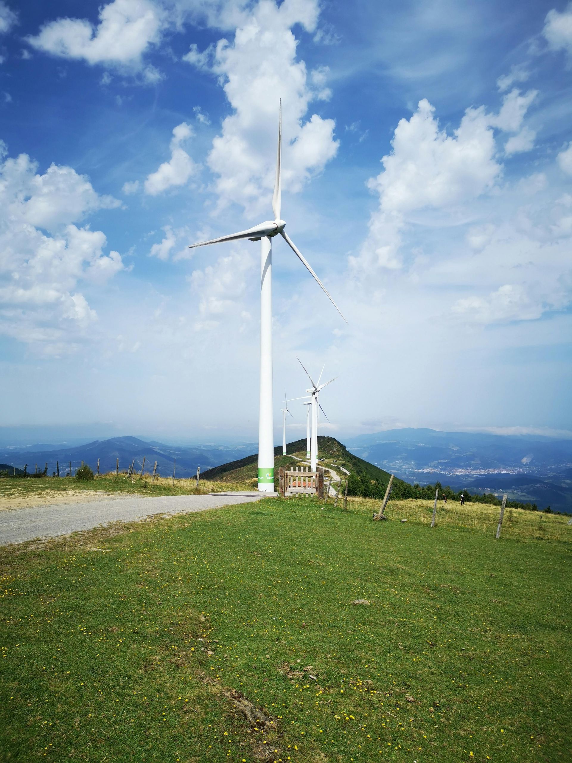 A wind turbine is sitting on top of a grassy hill.