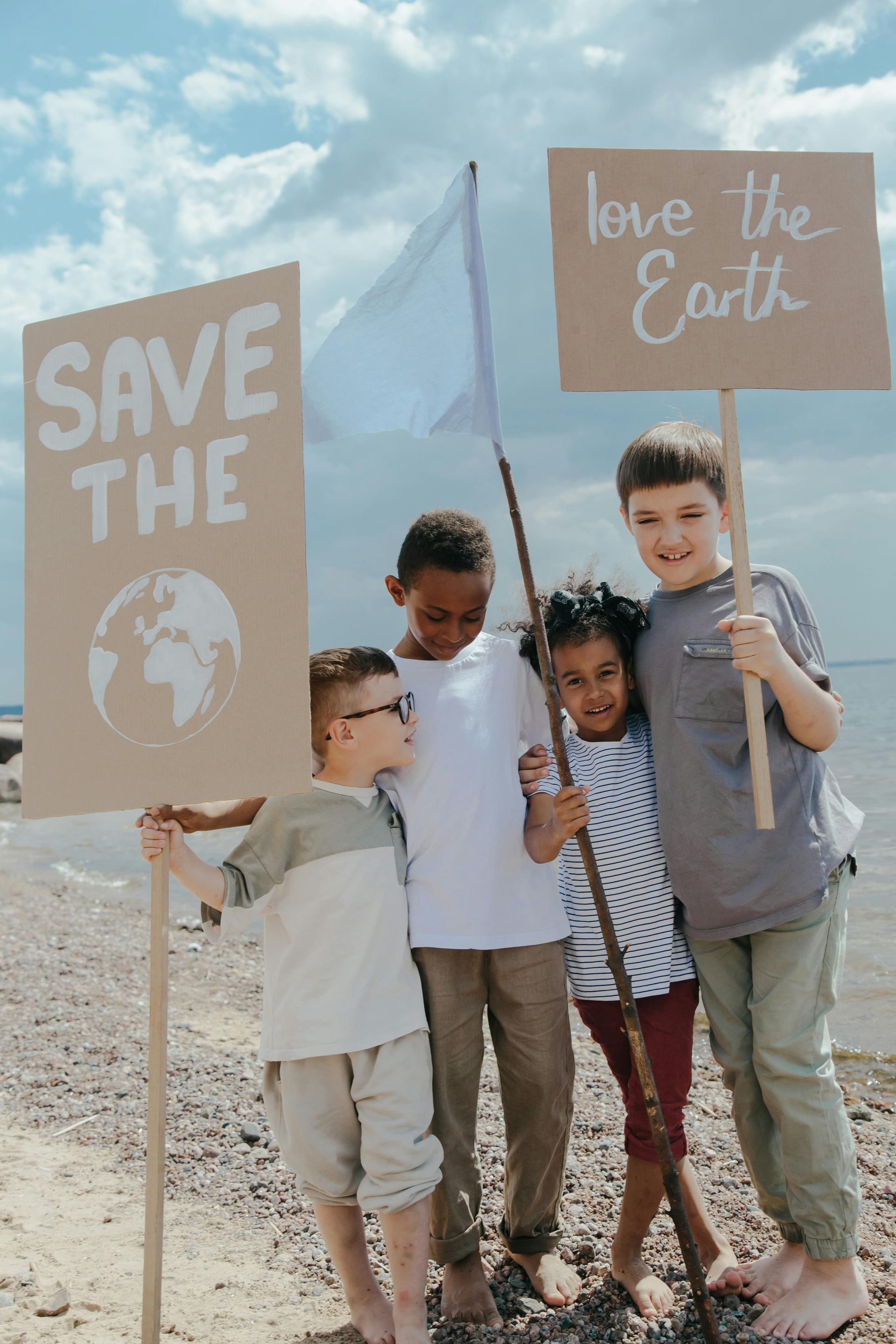 A group of children are holding signs on the beach.