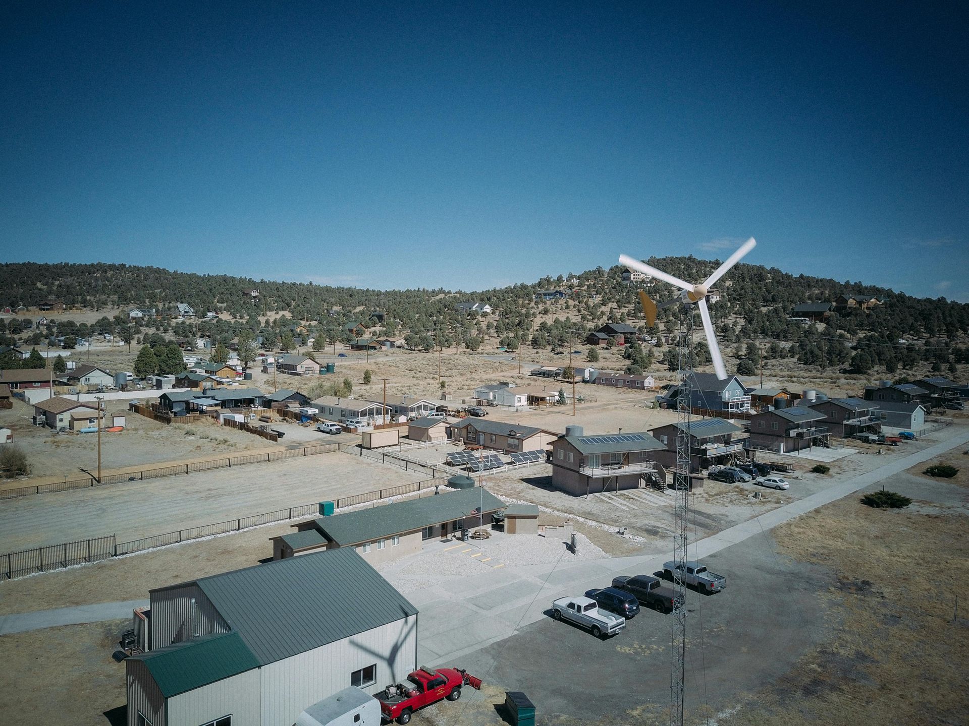 An aerial view of a small town with a wind turbine in the background.