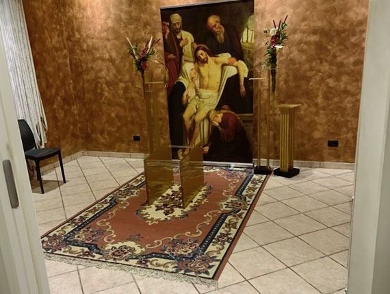 Una sala interna con un dipinto raffigurante Gesù deposto, posto sopra un tappeto decorato.
