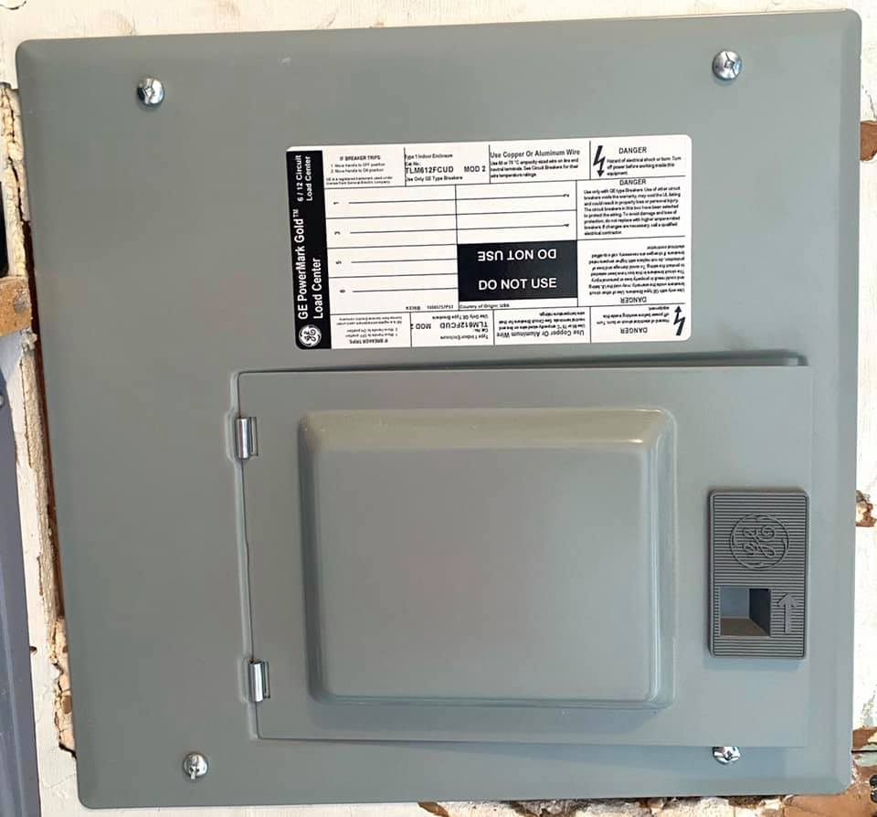 Woman in straw hat smiles, holding wine glass near a lake.