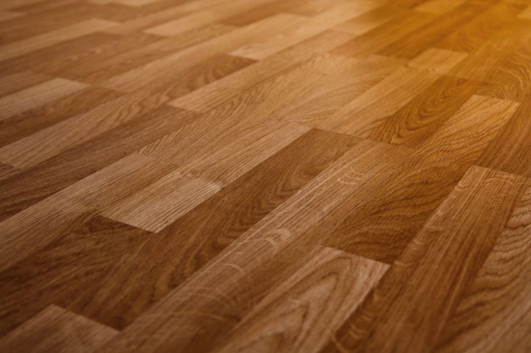 Pavimento in laminato effetto legno marrone dalle tonalità calde, con venature a vista, fotografato di profilo sotto una luce soffusa.
