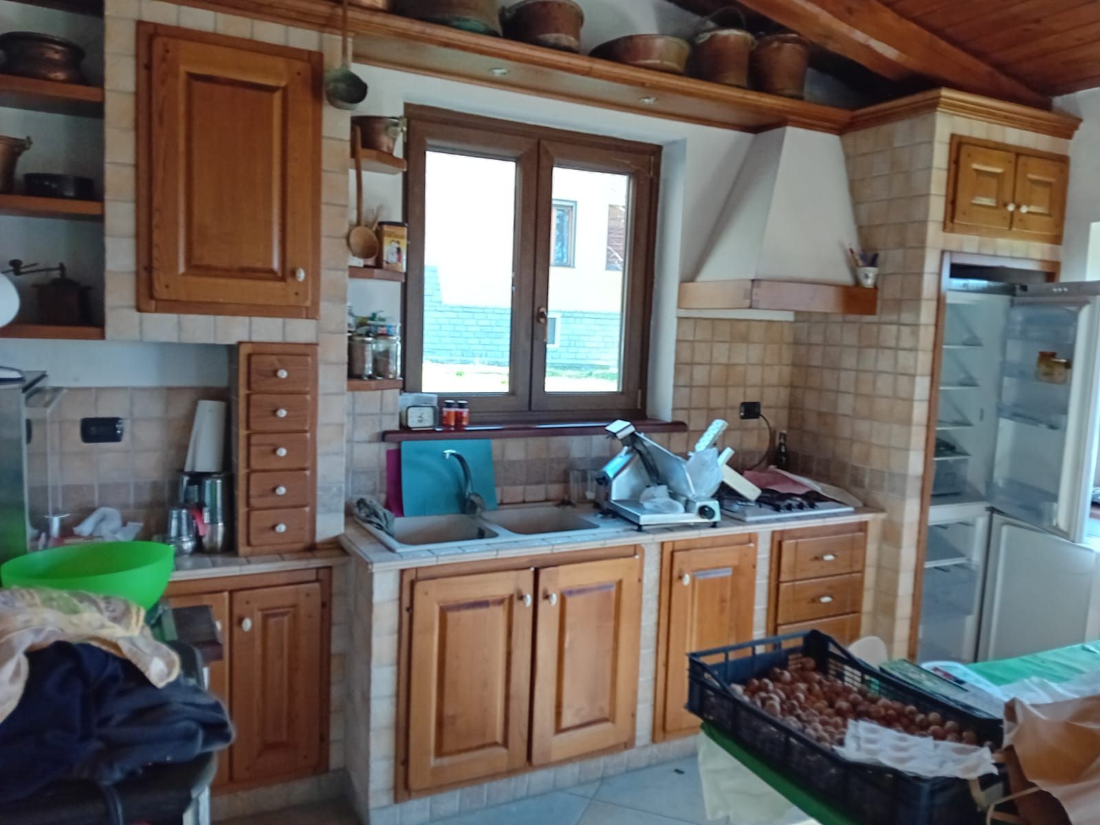 Una cucina luminosa e moderna con mobili in legno chiaro, paraschizzi in piastrelle bianche tipo metropolitana, lavello in stile rustico e piante in vaso.
