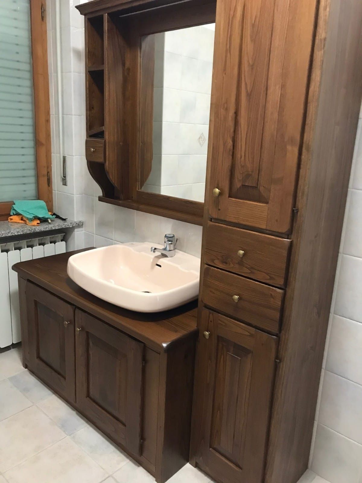 Bagno moderno con vasca freestanding nera, mobile lavabo in legno chiaro e ampia finestra con vista su un paesaggio suggestivo.