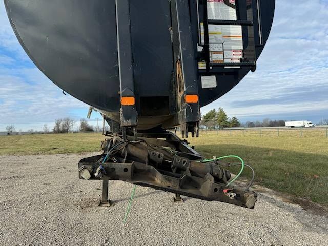 A large black tank is sitting on top of a trailer in a field.