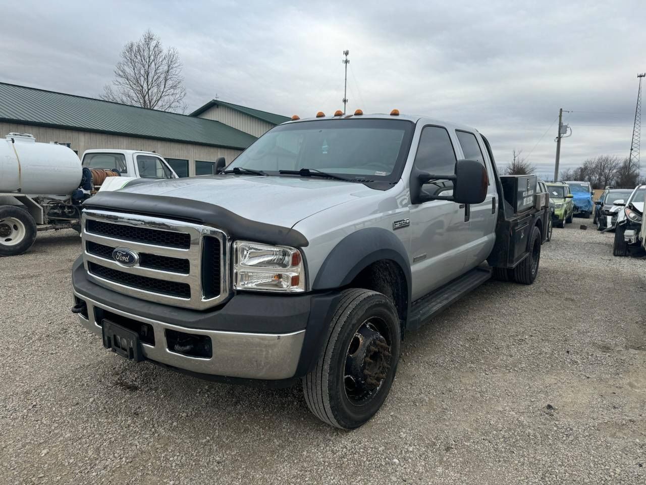 A silver ford truck is parked in a gravel lot.