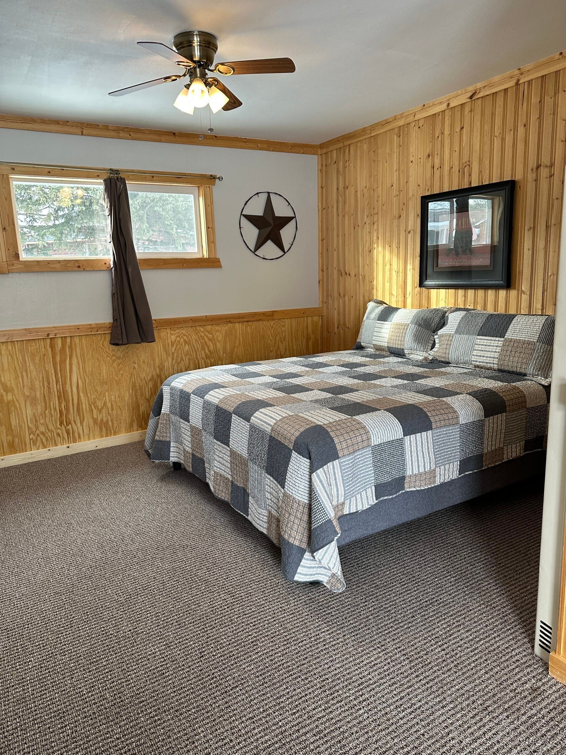 A bedroom with a king size bed and a ceiling fan.