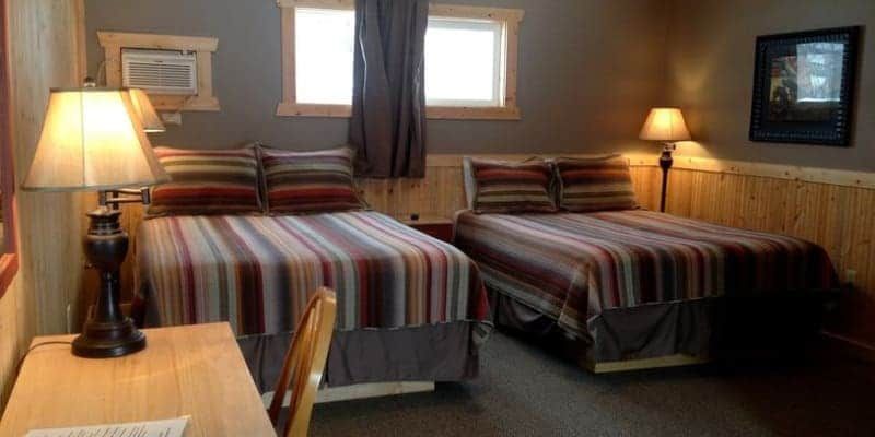 A hotel room with two beds , a desk and two lamps.