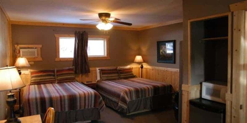 A hotel room with two beds and a ceiling fan.